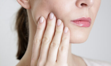 woman holding hand to jaw - botox for TMJ disorders